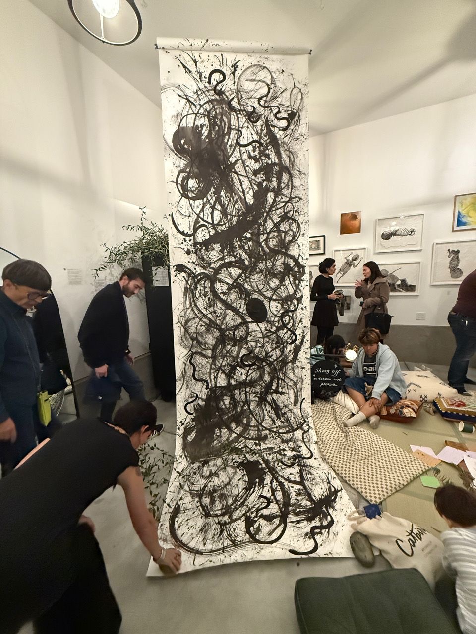 The ink scroll unfurled to the floor as guests sit on cushions nearby.