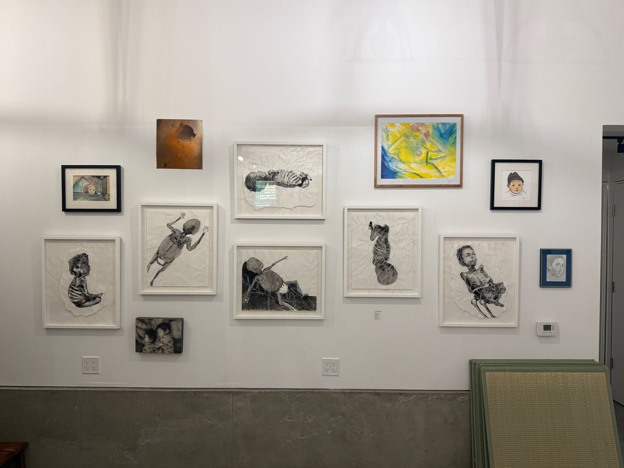 A salon-style wall of framed charcoal and watercolor works.