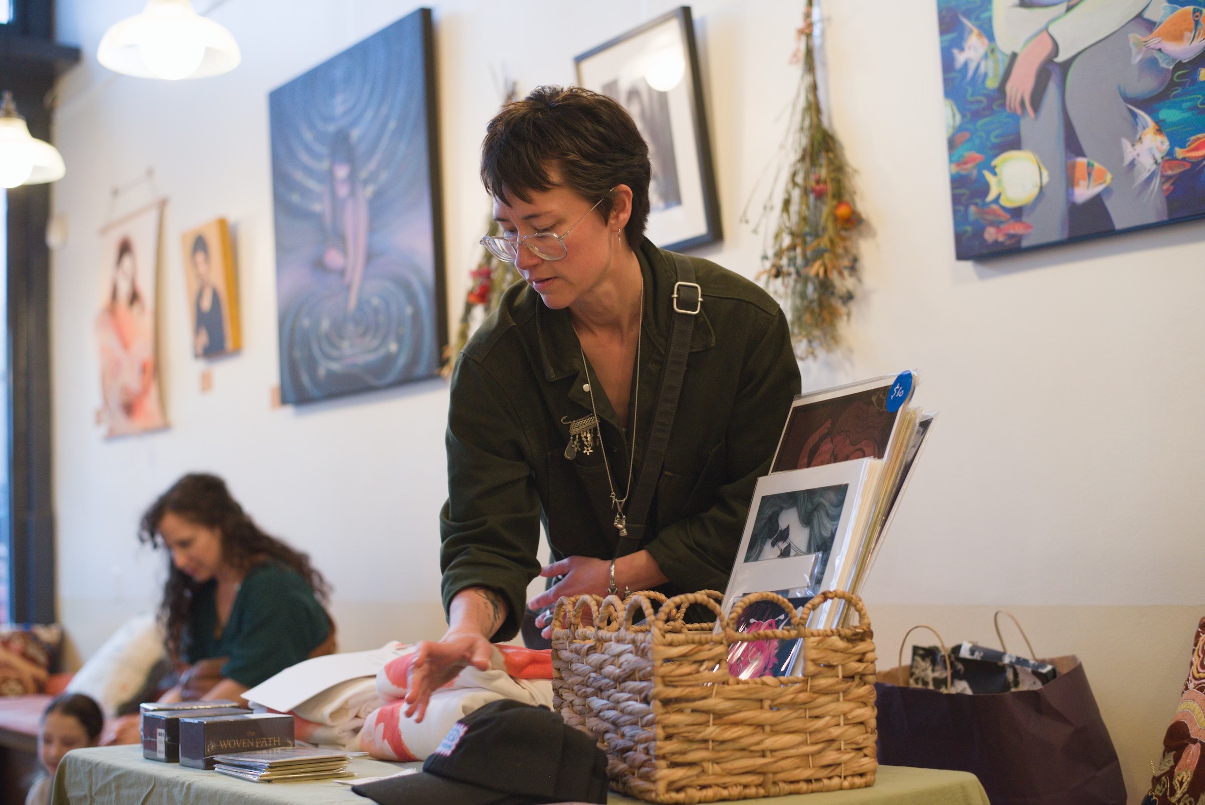 An artist arranging prints and goods at the merch table.